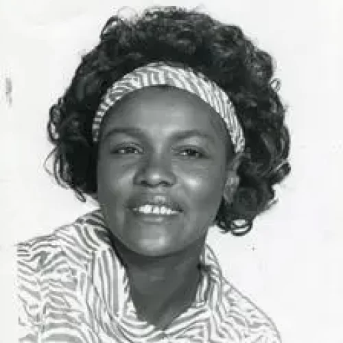 Imagene Stewart poses with a smile in a matching top and headband. Her hair is in loose curls behind her headband as she stairs off in the distance.