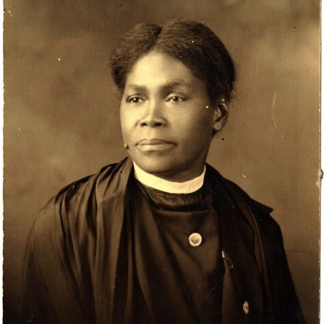 Anna E. Hall, wearing a clerical collar, with her hair pulled back. Photo is in sepia tones.
