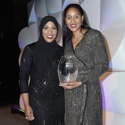 Ibtihaj Muhammad on left with Maya Moore on right. Ibtihaj is wearing a black hijab and smiling. Maya is holding a trophy. They are at The Women's Sports Foundation's 38th Annual Salute To Women in Sports Awards Gala on October 18, 2017 in New York.