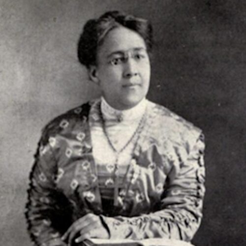 Florence Spearing Randolph wearing her hair up, glasses, a silky appearing dress with a lacy shirt, a brooch, and a necklace. The photo is in black and white.