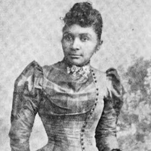 Clarissa Minnie Thompson Allen wearing her hair in an updo with curly bangs, a high-necked, formal dress with buttons down her left front, puffed sleeves, earrings, and a flowered choker. The photo is in black and white.