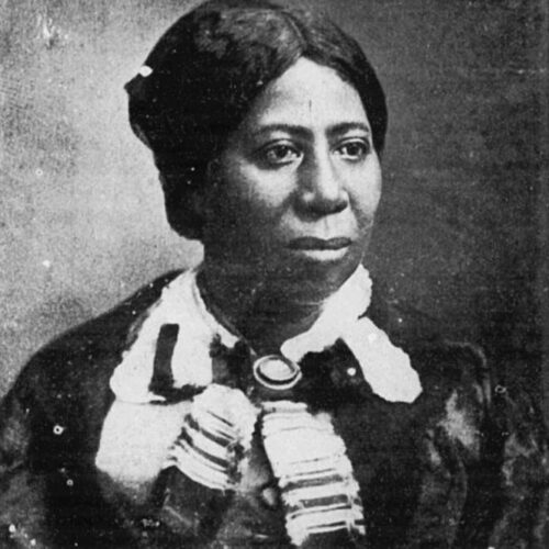 Anna Murray Douglass looking toward her left, wearing her hair parted in the middle and pulled back, with a white collar, cape, and a brooch. The photo is in black and white.
