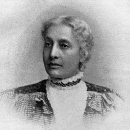 Harriet Forten Purvis looking to her left, wearing her hair parted and pulled back, and a striped ruffled top with a light-colored high-necked collar. The photo is in black and white.